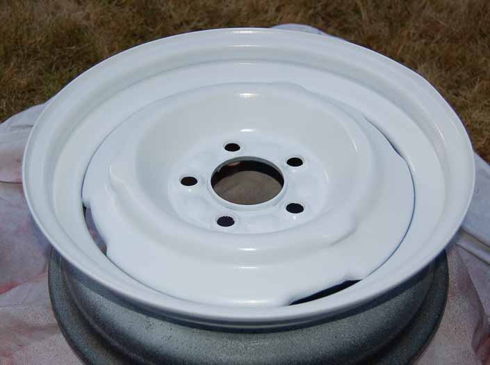Picture of the restored trailer wheel that has been painted with 4 coats of gloss white paint from aerosol spray paint cans